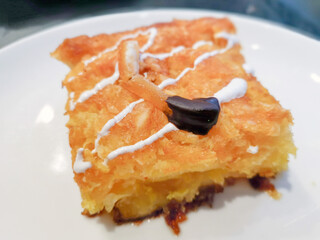 Delicious sweet orange cake, traditional greek pastry baked with orange pieces and honey, served in white plate.