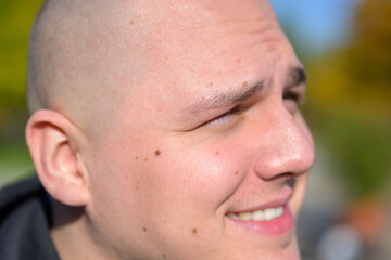 Smiling young man with shaved head outdoors