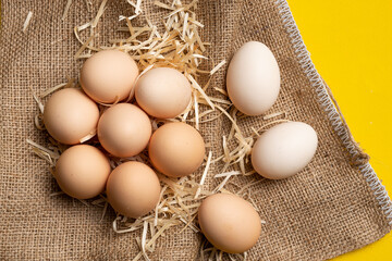 Raw organic farm eggs, straw and burlap. Natural healthy food and organic farming concept.