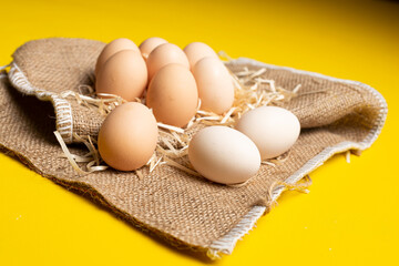 Raw organic farm eggs, straw and burlap. Natural healthy food and organic farming concept.