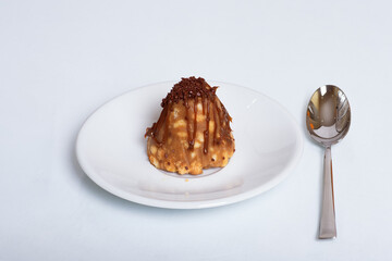 Traditional Russian cake or Anthill pastry on a white plate with a spoon on a white background. Unhealthy food concept