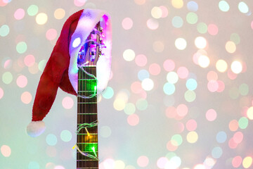 acoustic guitar with red Santa hat and light colorful garland. Christmas music concept