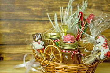 Christmas food gift basket. Edible Christmas gift made of cookies, honey, homemade handmade sweets, dried oranges, lollipops on a wooden table.Concept handmade christmas gifts, Handmade food presents