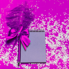 Notebook with a beautiful pen on a purple background with sparkles.