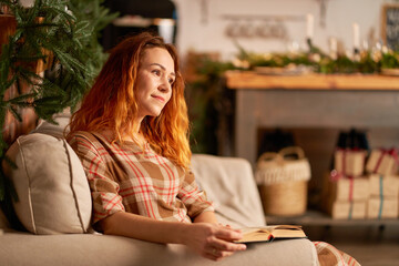 A cute girl is reading a book in a warm and cozy atmosphere. Relaxation and privacy concept