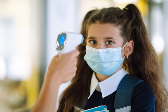 Temperature screening and medical check at school. Teacher with thermometer at school entrance. Covid-19.