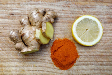 Healthy, fresh ingredients like ginger, turmeric and lemon on wooden background.