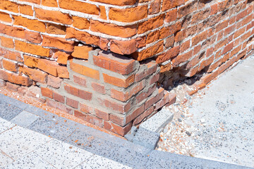 Restoration of an old red brick wall with new brick