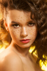 Creative winter makeup with golden snowflakes on her face and wavy hairstyle