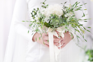 Selective focus the bride's hand holding the wedding bouquet White and green tones. The elegant simplicity of the happy day.