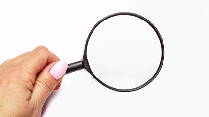 Woman's hand holding a magnifying glass on a light background