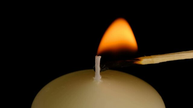 Large thick white candle lit and burn on a black background high resolution video clip macro shooting close-up