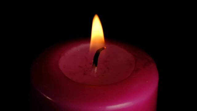 Large thick red candle lit and burn on a black background high resolution video clip macro shooting close-up