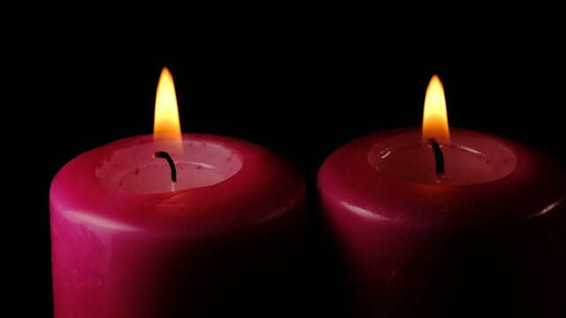 Large thick candles are lit and burn on a black background high resolution video clip macro shooting close-up