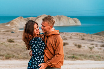 Attractive couple man and woman embrace at twilight near the sea and mountain view. Romantic moment on vacation