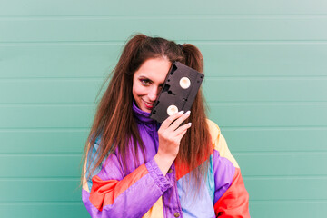 Stylish girl in a sports jacket of the 90s and a VHS tape. Portrait of a fashionable woman near the...