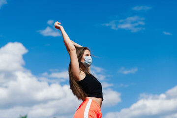 Obraz na płótnie Canvas Young fit female in sportswear and protective mask for coronavirus on track during outdoor workout