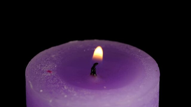 Large thick lilac candle lit and burn on a black background high resolution video clip macro shooting close-up