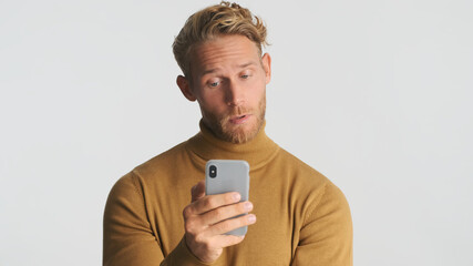 Young bearded man wear turtleneck using smartphone for online business communication isolated on white background. Modern technology concept