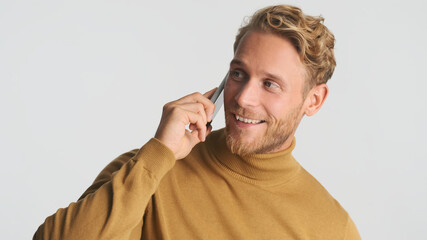 Handsome bearded man wear turtleneck talking on smartphone with best friend and smiling over white background. Always in touch