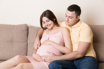 Happy pregnant woman and her husband waiting for baby at the home. happy family love and care concept