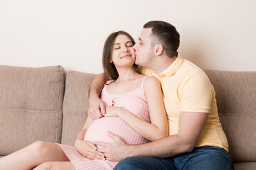 Happy pregnant woman and her husband waiting for baby at the home. happy family love and care concept