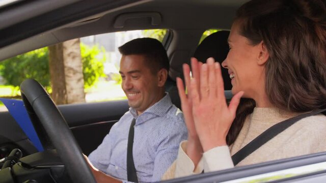 driver courses, exam and people concept - woman and driving school instructor with clipboard talking and shaking hands in car