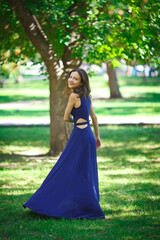 Obraz na płótnie Canvas Girl in a blue dress walks in the park