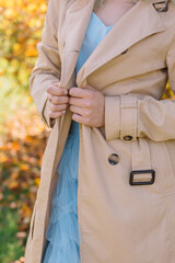 Beige coat on a woman on an autumn sunny day
