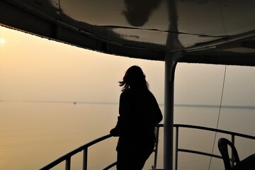 Long hair Women enjoying sunset in the sea alone standing on  the deck of a launch 