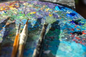 Stock Photo of a painter brushes and palette knife on a wooden palette with mixed and unmixed oil...