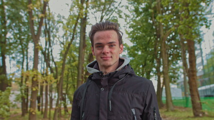 Teenage boy smiling outdoors. Young boy smiling on a road in the woods. Portrait of a happy handsome young boy looking into the camera.