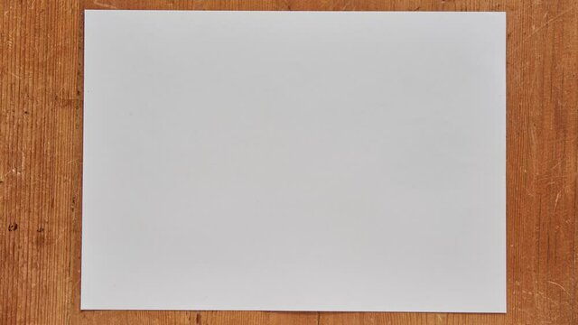 Crumpled paper ball in stop motion on a wooden table. Crumpling up a sheet into a paper ball. Crumpled paper stop motion. Crumple paper stop motion animation. Discarding a draft in stop motion.