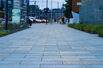 Modern urban environment with a pedestrian walkway of square stone tiles and a busy street blurred in the background