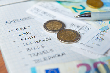 List of daily living expenses, with receipts, notes and coins next to it.