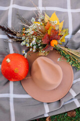orange pumpkin hat and autumn leaves of different colors lie on a blanket