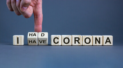 Symbol for a succesful corona treatment. Hand turns cubes and changes the expression 'I have corona' to 'I had corona'. Beautiful grey background, copy space. Medical and covid-19 pandemic concept.