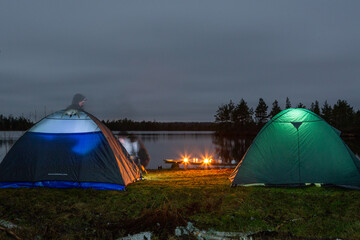 Tents near forest lake in day and night time