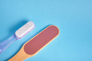 sandpaper for feet with wooden handle and plastic pumice stone with foot brush on blue background