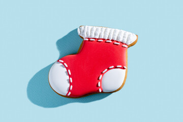 Christmas decorated cookies. New Year stocking. Festive pastry. Traditional winter sweets. Gingerbread biscuit figure boot sock red white icing isolated on blue pastel.
