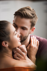 tender man touching face of beloved woman on blurred foreground