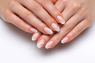 French wedding white manicure with crystals on long oval nails close-up on a white background. Abstraction design on nails.