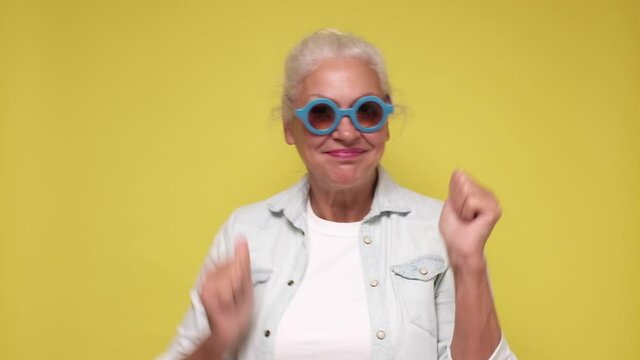 Happy senior woman in sunglasses having fun dancing