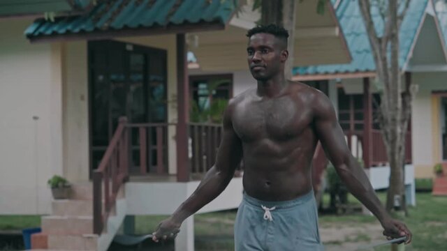 African American athlete man doing jumping rope workout outdoor. Handsome young sportsman skipping rope at backyard in slow motion