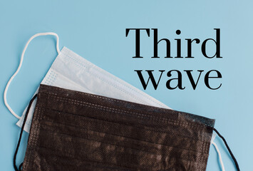 text third wave on a blue background with respiratory protective face masks