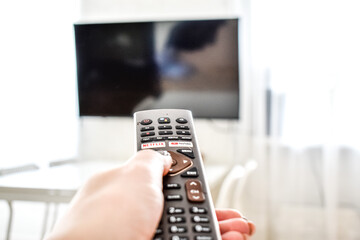 The remote control from the TV in the girl's hand directs to turn on the screen at home.