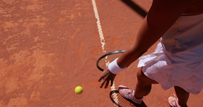 Woman bouncing ball before serving on tennis court
