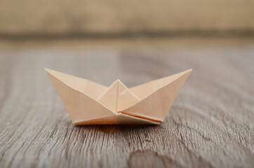 Origami brown paper boat isolated on woden background