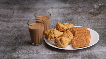 cutting masala chai or tea served with puff pastry/ khari and biscuits.