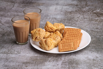 cutting masala chai or tea served with puff pastry/ khari and biscuits.